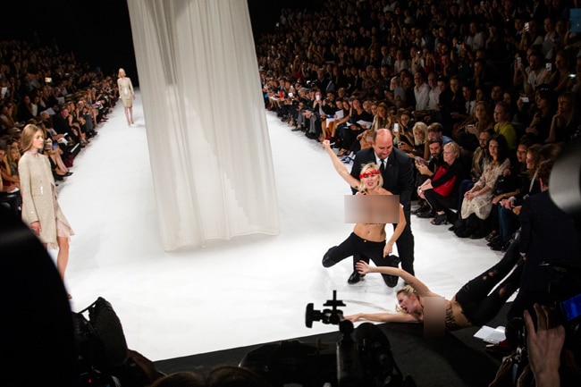 पेरिस फैशन शो में घुसी टॉपलेस महिला प्रदर्शनकारी