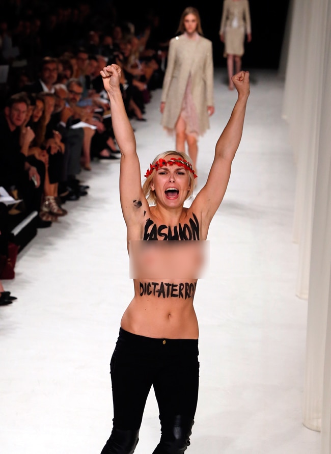 पेरिस फैशन शो में घुसी टॉपलेस महिला प्रदर्शनकारी