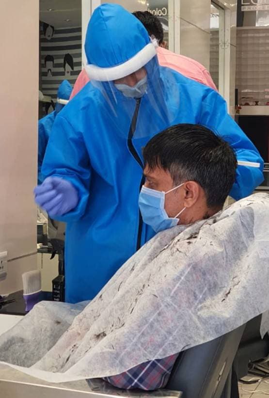 PPE किट पहन काट रहे बाल, ग्राहक को डिस्पोजेबल कपड़े से कर रहे कवर