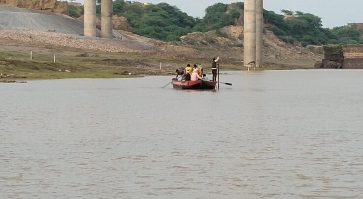 नाव से नदी में लोहे के जाल डालकर युवकों को तलाशने में जुटी पुलिस.