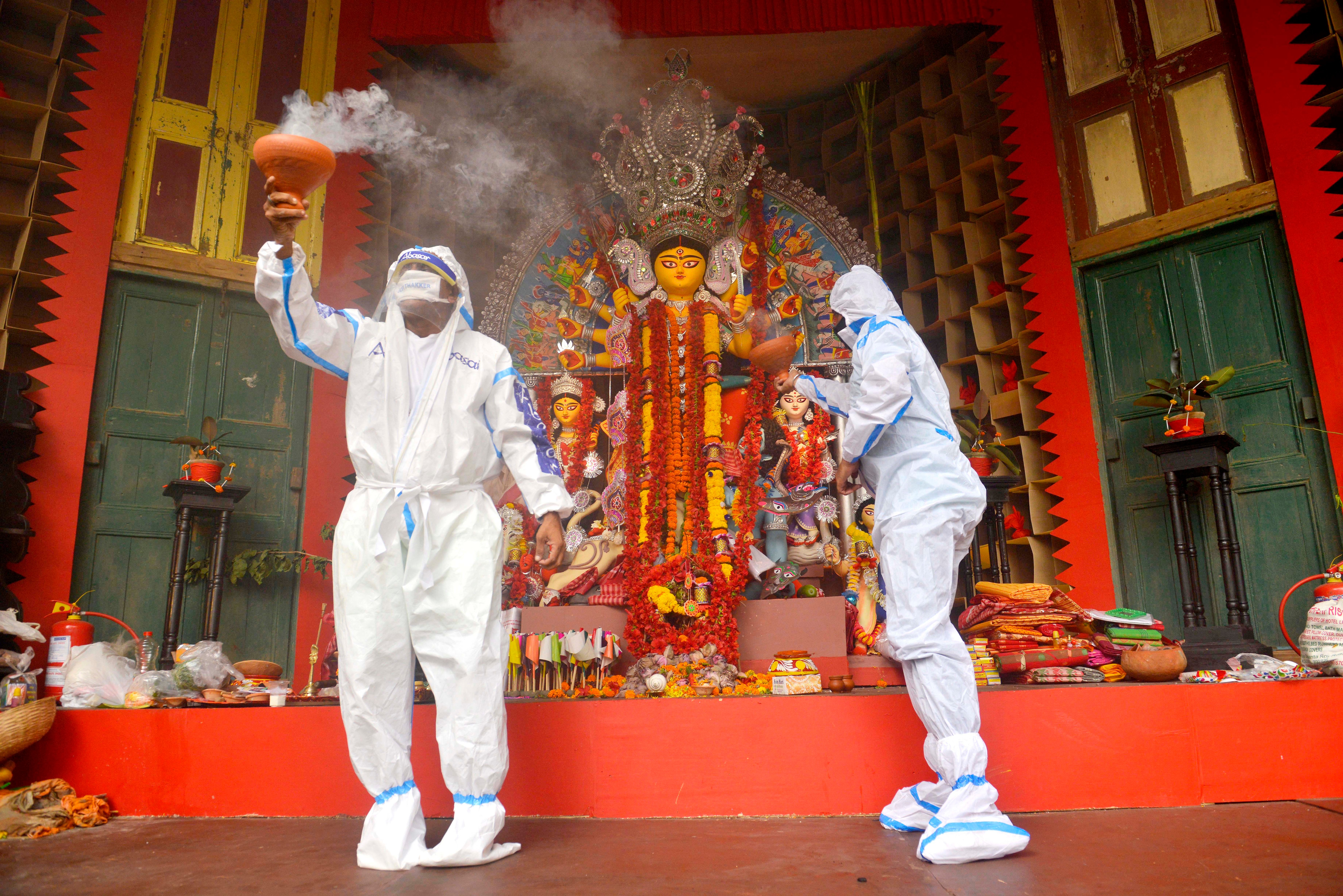 पीपीई किट पहन कर धुनुची डांस करते नृतक 