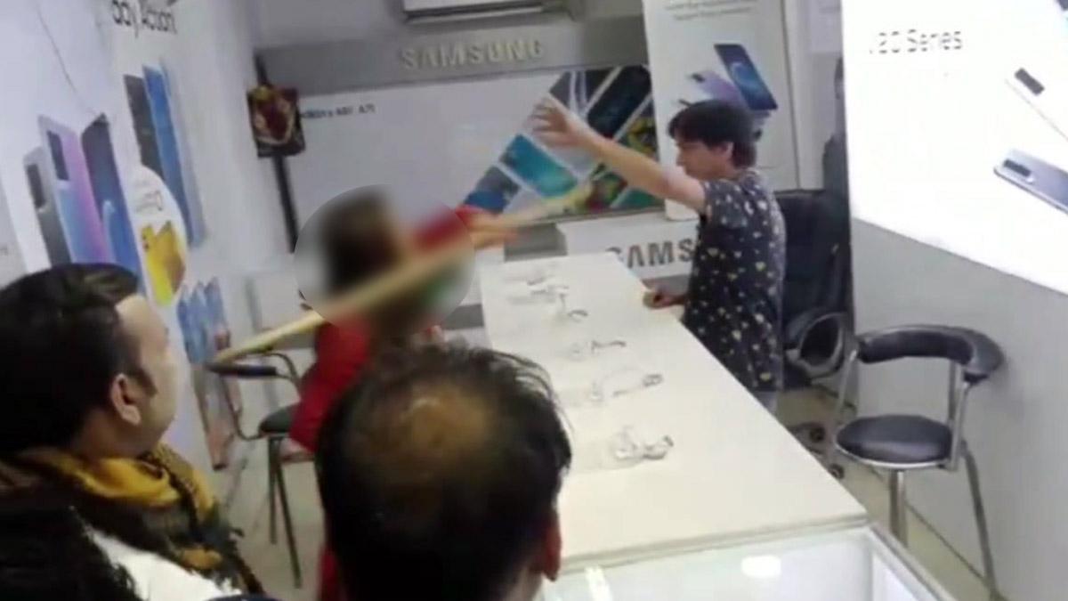 महिला ने दुकानदार को डंडे से पीटा (फोटो- वायरल वीडियो ग्रैब)