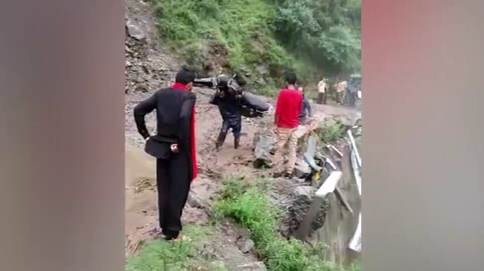 कंधे पर बाईक को लेकर सड़क पार करता शख्स