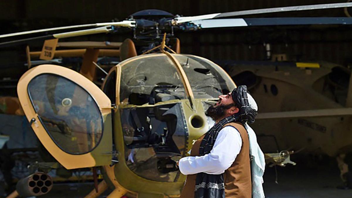 काबुल में खराब हेलिकॉप्टर के पास खड़ा शख्स 