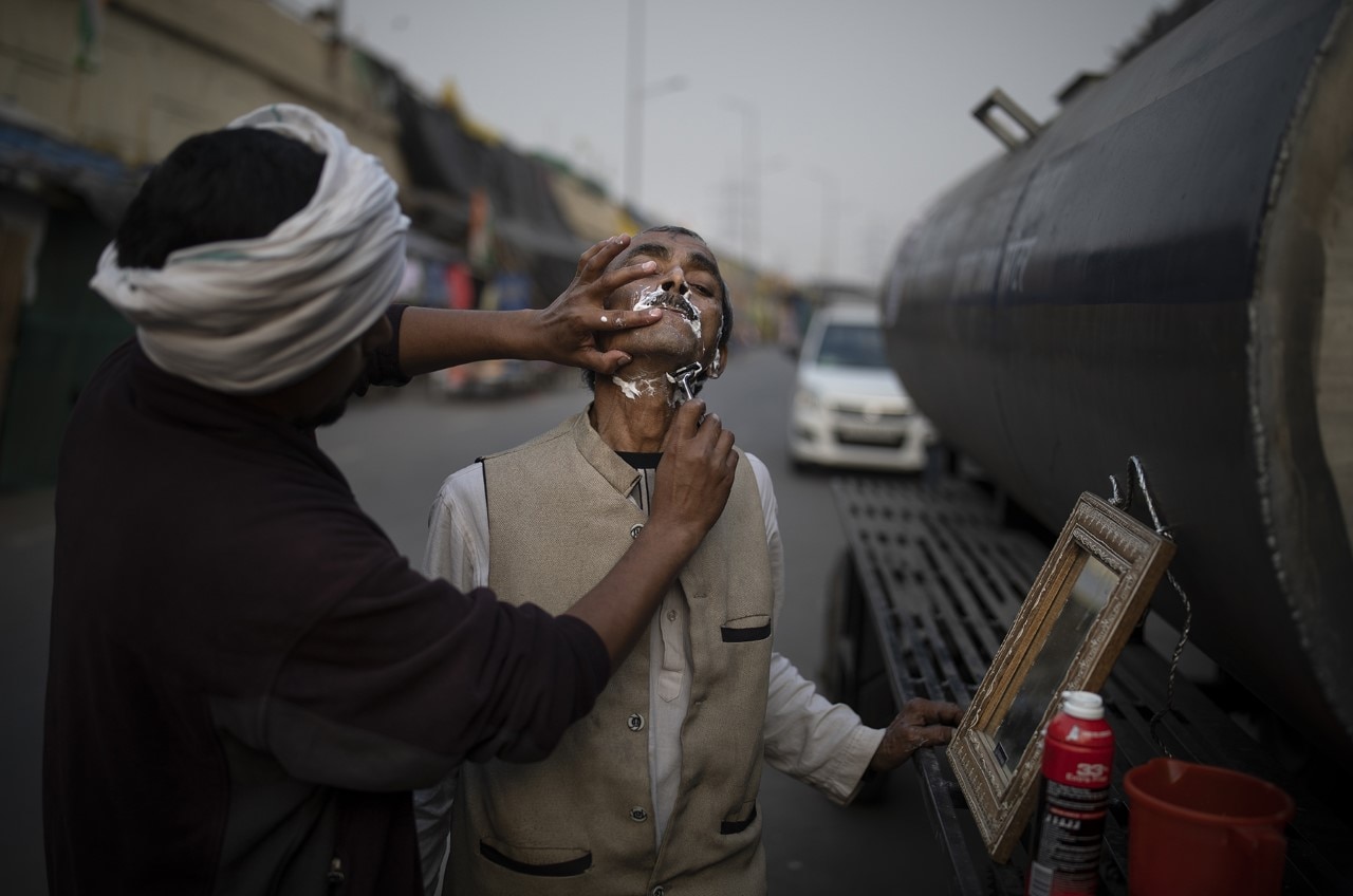 गाजीपुर बॉर्डर पर शेविंग करवाता एक प्रदर्शनकारी