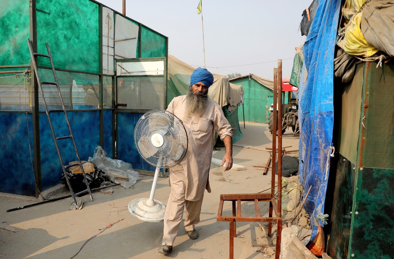 सिंघु बॉर्डर पर अपना पंखा ले जाता एक प्रदर्शनकारी किसान