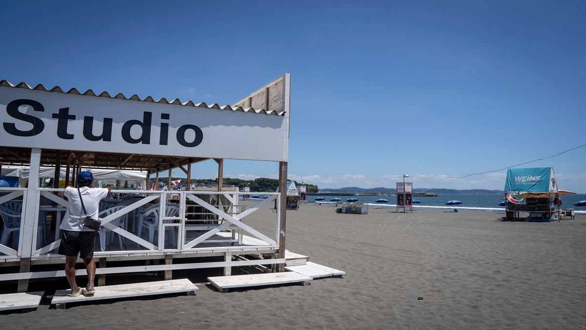 A parasol shop worker looks at the sea on an empty beach due to a tsunami warning in Fujisawa city, Japan (Photo-AFP)