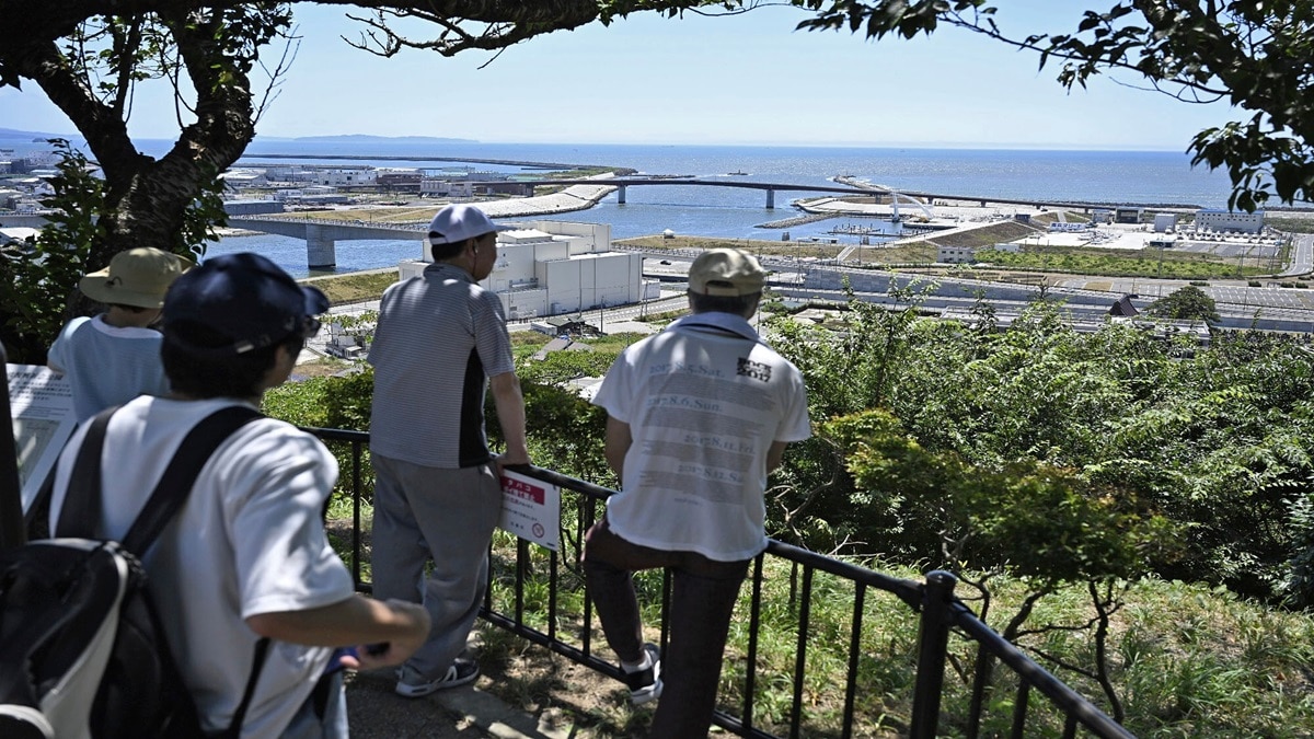People who evacuated to Hiyoriyama mountain watch toward the sea in Ishinomaki, Miyagi prefecture, northern Japan (Phto- Kyodo News via AP)