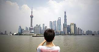 शंघाई के गगनचुंबी इमारतों की तस्वीर लेता एक टूरिस्ट