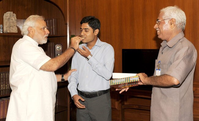 राजेश कुमार को मिठाई खि‍लाते प्रधानमंत्री नरेंद मोदी