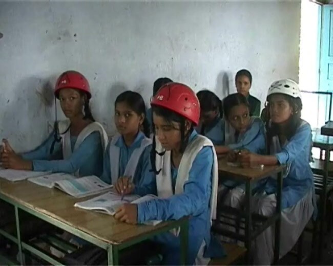 स्कूल में हेलमेट लगाकर क्लास करते बच्चे