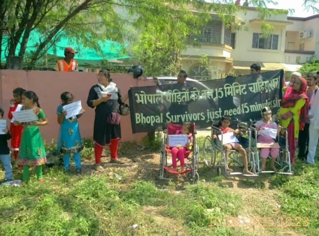 बैनर लेकर सड़क किनारे खड़े भोपाल गैस त्रासदी के पीड़ित