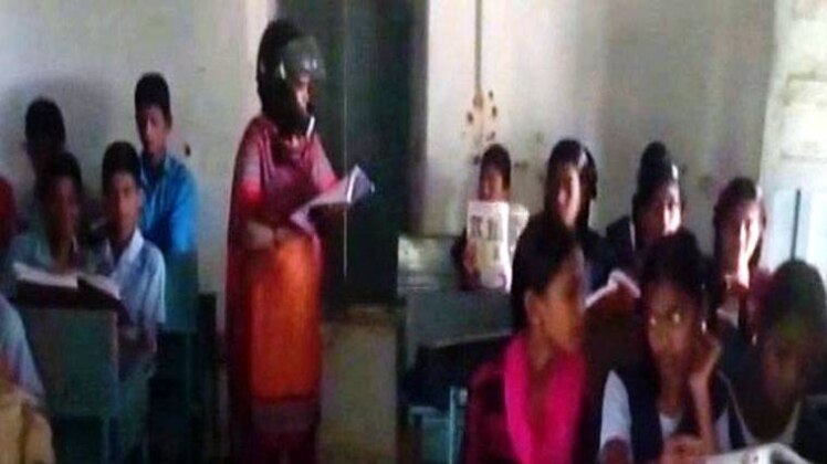 हेलमेट पहनकर बच्चों को पढ़ाती टीचर 