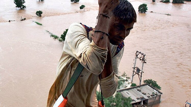 मुसीबत में सहारा गुजरात में एक बाढ़ पीड़ित को हेलिकॉप्टर से निकालता बचाव दल