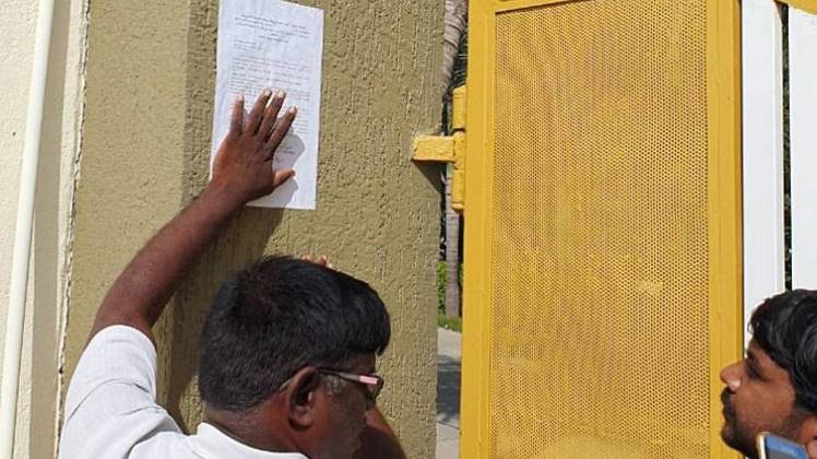 बिल्डिंग पर नोटिस चस्पा करते अधिकारी (आशीष पांडेय)