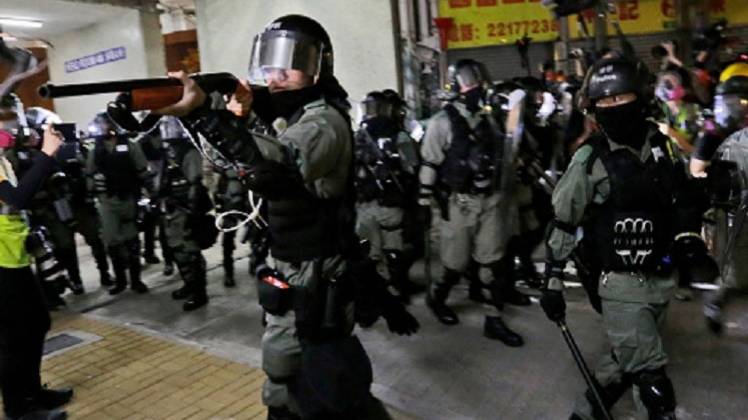 प्रदर्शनकारियों पर फायरिंग करता हांगकांग पुलिस का सिपाही (PTI)