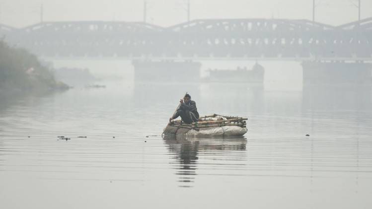यमुना नदी में नाव पर बैठा शख्स (फोटो- PTI)
