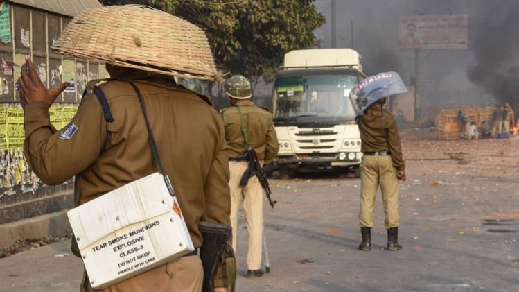 भजनपुरा के चांद बाग इलाके में पत्थरबाजी से खुद का बचाव करता पुलिसकर्मी (फोटो-PTI)