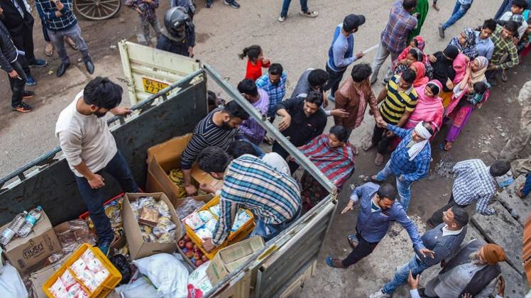 दिल्ली हिंसा पीड़ितों के बीच राहत सामग्री बांटते लोग (फोटो- पीटीआई)
