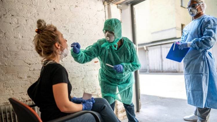 जर्मनी के बर्लिन में कोरोना टेस्ट के लिए संदिग्ध मरीज का सैम्पल लेते स्वास्थ्यकर्मी 