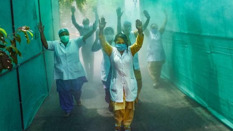 दिल्ली के हिंदू राव अस्पताल में सैनिटाइजेशन प्रक्रिया से गुजरतीं नर्स (फोटो-PTI)