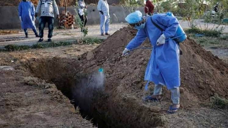 कोरोना संक्रमण से मरने वाले की कब्र को सेनेटाइज करते हुए (फोटो-PTI)