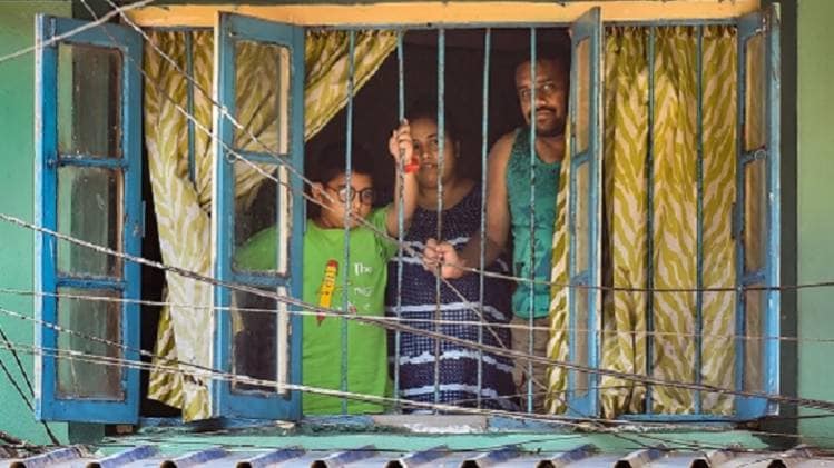 कोलकाता में लॉकडाउन के दौरान अपने घर की खिड़की से बाहर देखता एक परिवार (फोटोः PTI)