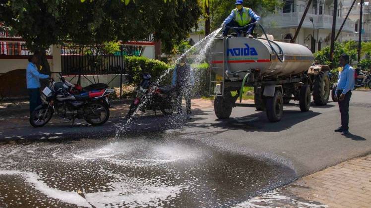 नोएडा में एक सड़क को साफ करते निगम के कर्मचारी (फोटो- पीटीआई)