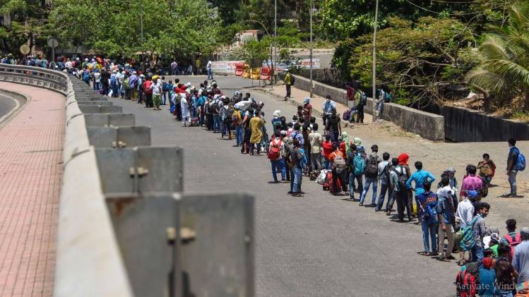 मुंबई में रेलवे स्टेशन के बाहर घर जाने के लिए कतार में लगे मजदूर (फोटो- पीटीआई)