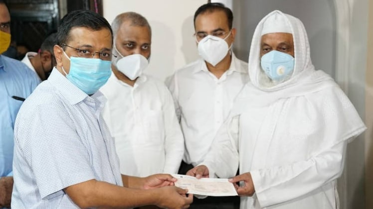 डॉ जावेद अली के परिजनों को चेक देते सीएम केजरीवाल (फोटो- ट्विटर)