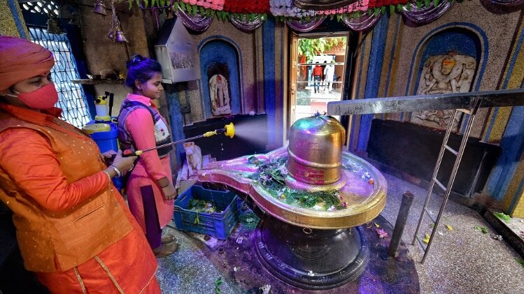 शिवालयों को सैनिटाइट करते श्रद्धालु (फोटो-PTI)