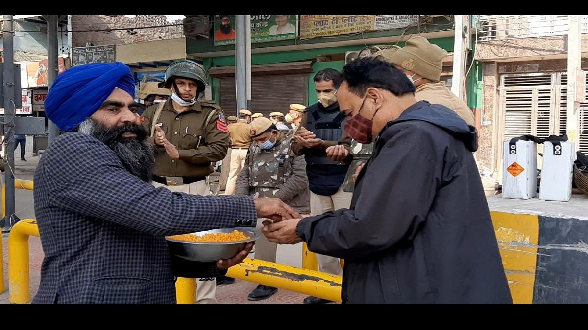 दिल्ली पुलिस के जवानों को प्रसाद बांटता किसान