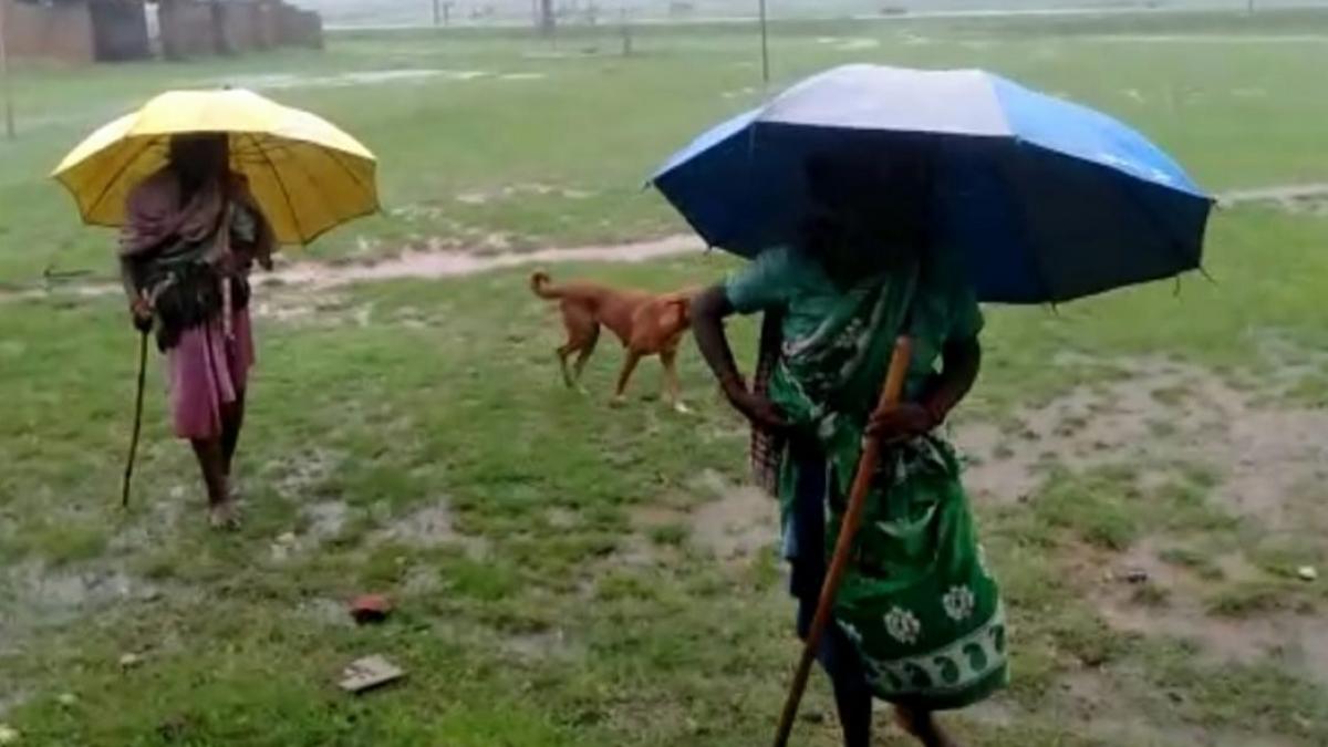 भारी बारिश के बीच छाता लेकर वैक्सीनेशन सेंटर जातीं बुजुर्ग महिलाएं