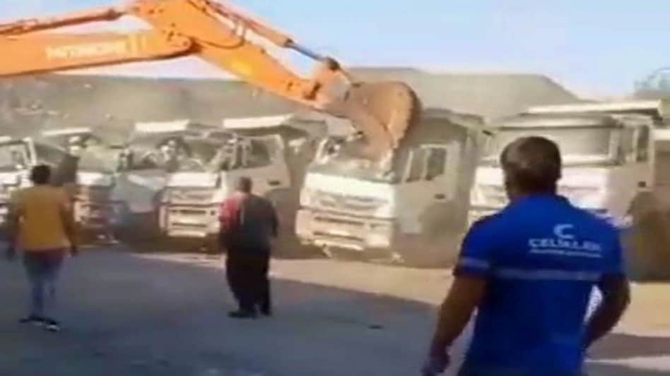 ट्रकों को जेसीबी से तोड़ता शख्स