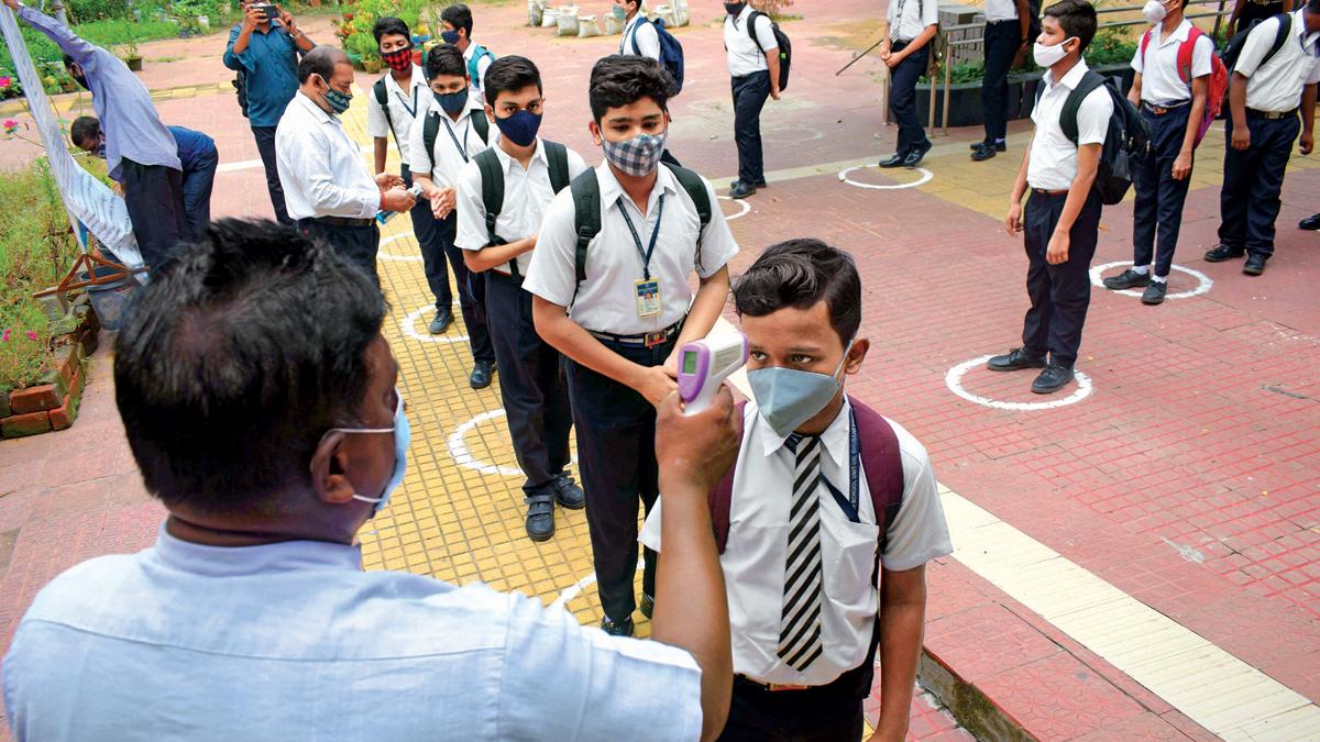 दूर-दूर से ओडिशा में भुवनेश्वर के एक स्कूल में प्रवेश से पहले तापमान की जांच कराते छात्र