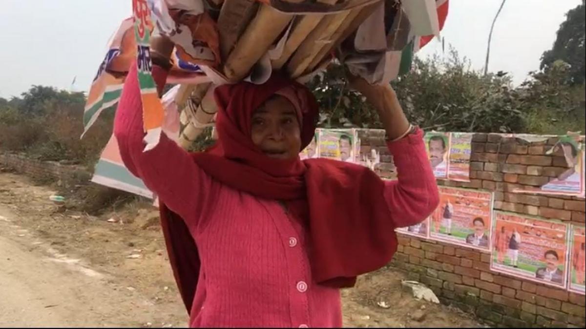 बीजेपी की होर्डिंग लेकर घर जाती महिला