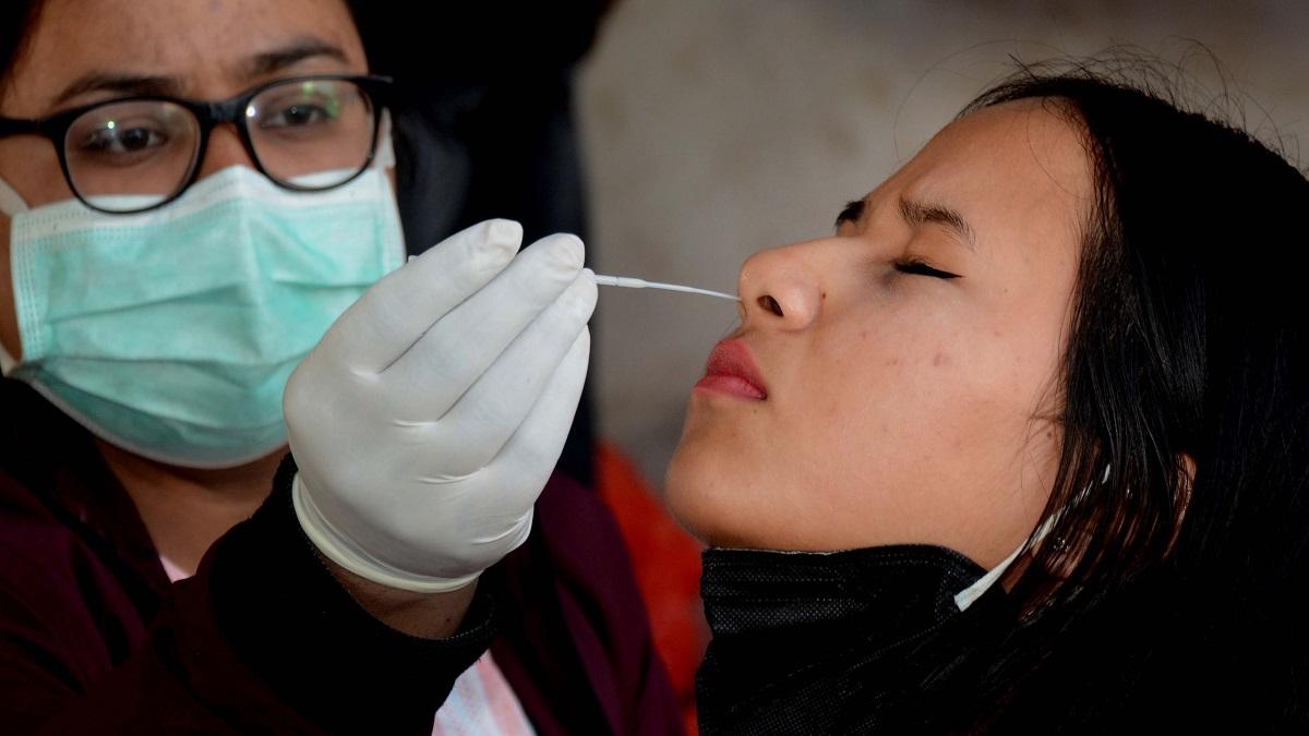 गुवाहाटी: कोरोना जांच के लिए एक पैदल यात्री का सैंपल लेते हुए हेल्थ वर्कर.     (Photo: PTI)