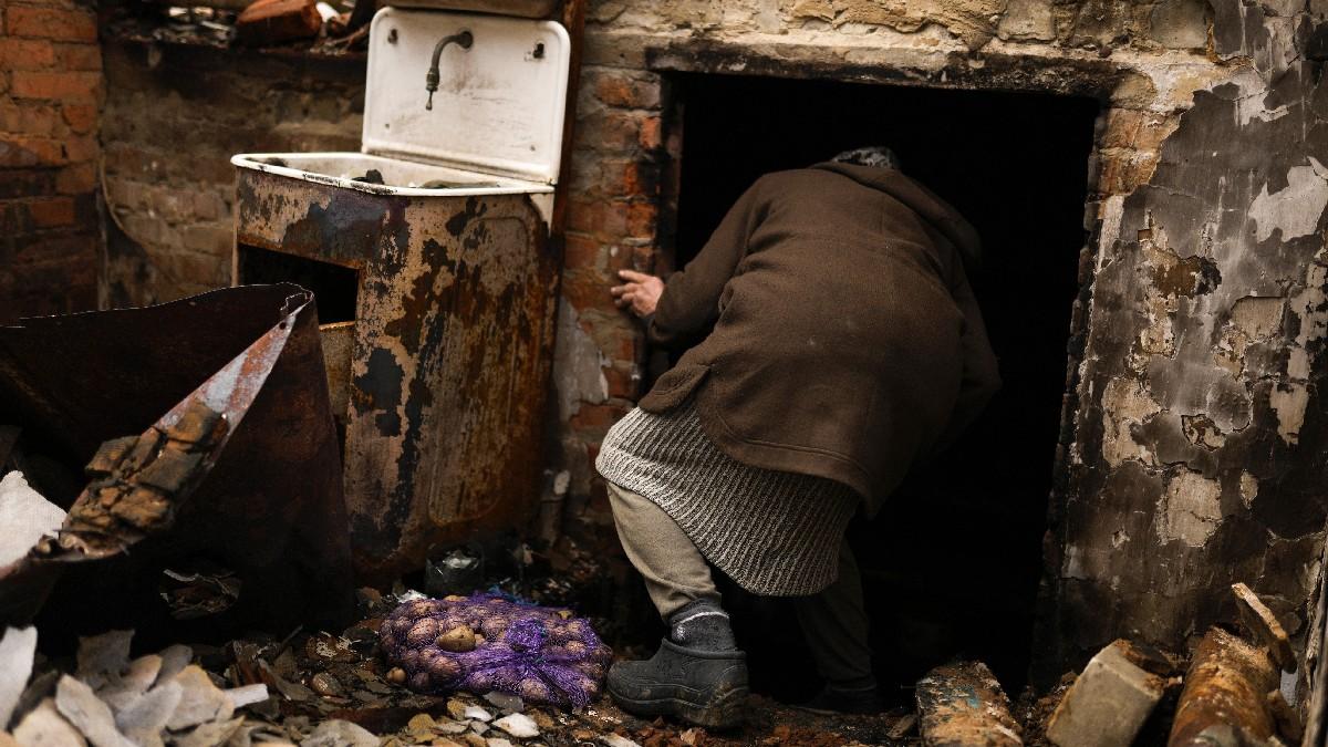 यूक्रेन के चेर्निहाइव शहर में अपना घर बर्बाद होने के बाद मकान के नीचे बनी सुरंग में जाती महिला.