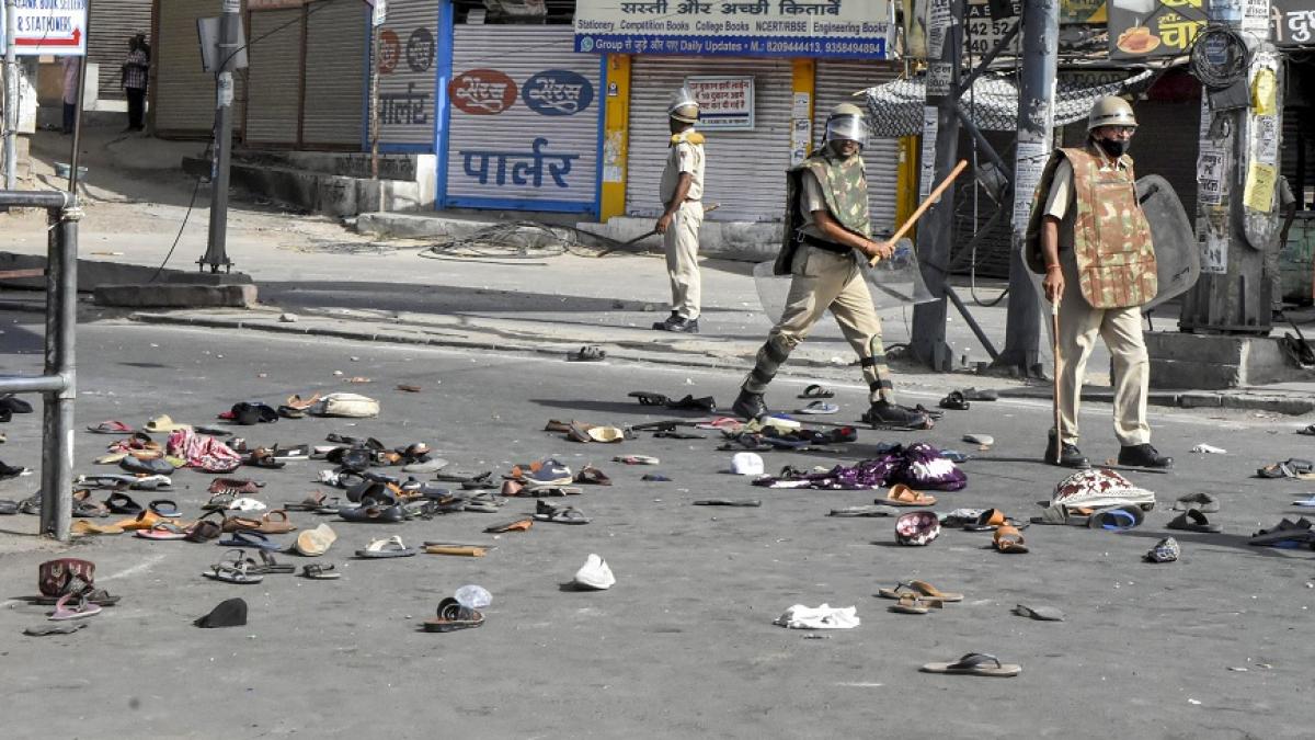 जोधपुर हिंसा के बाद सड़क पर बिखरे चप्पल और तैनात पुलिसकर्मी (फोटोः पीटीआई)