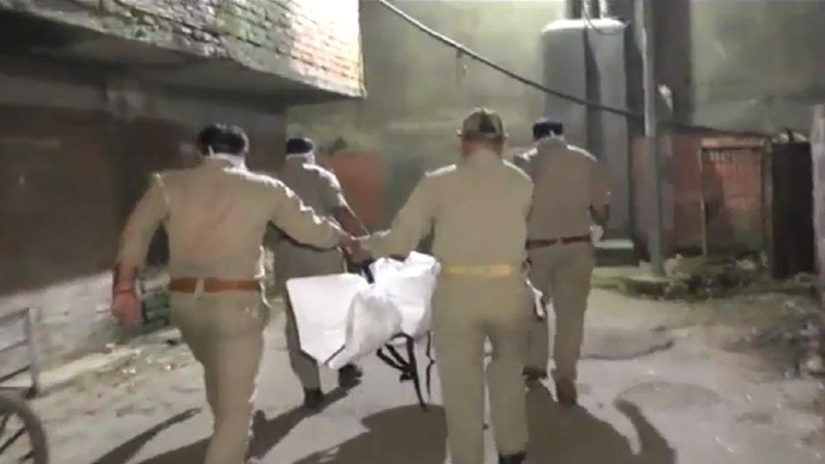 बच्चे की डेडबॉडी ले जाते पुलिसकर्मी.