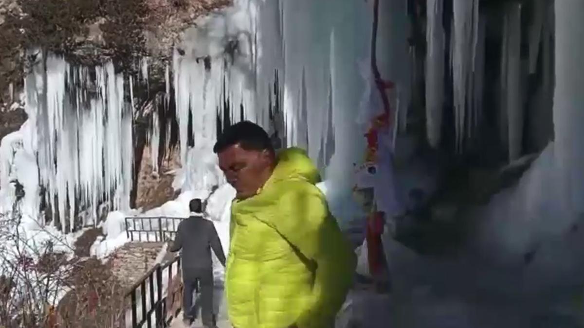 उत्तराखंड में निति घाटी में बर्फ के पहाड़ के पास से गुजरते पर्यटक.  