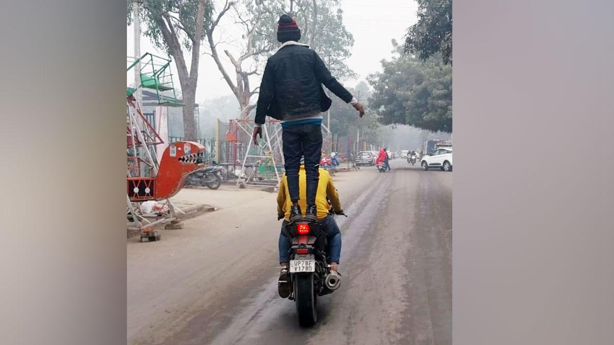 चलती बाइक पर स्टंट करता युवक