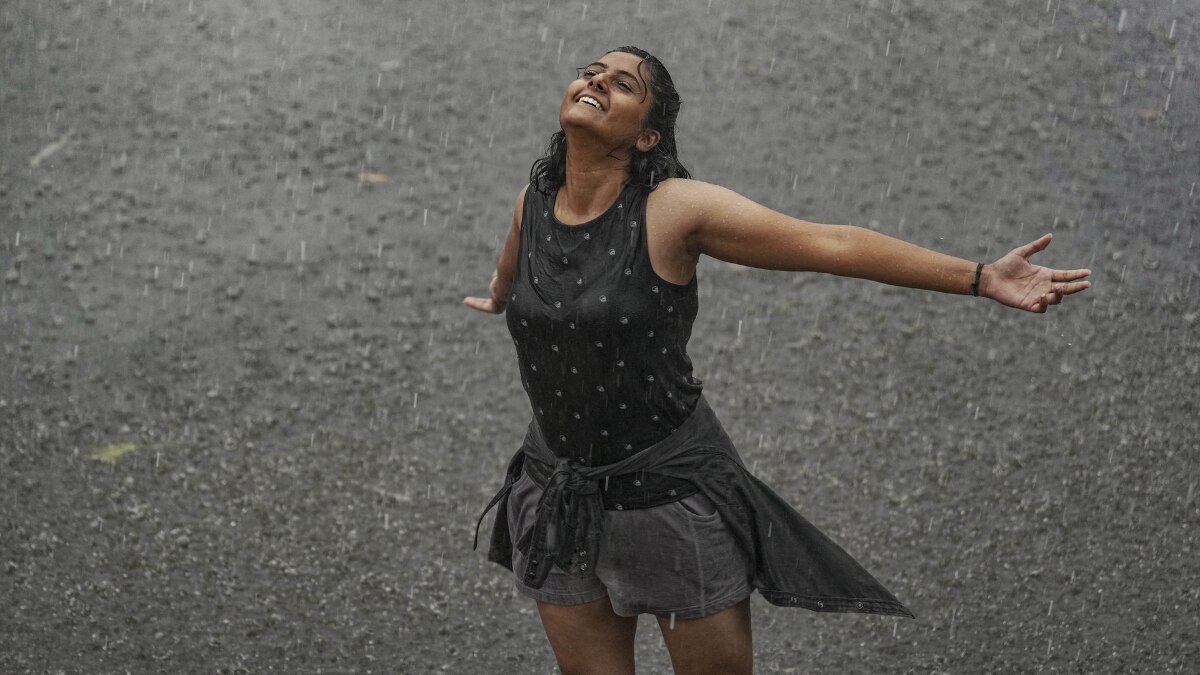 मुंबई में शनिवार को तेज बारिश हुई है. यहां छत्रपति शिवाजी महाराज टर्मिनस के पास बारिश का आनंद लेती एक महिला. (फोटो- पीटीआई )