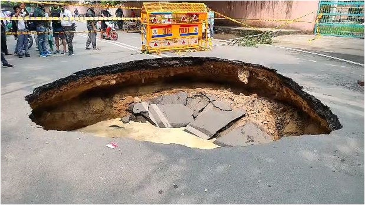 सड़क धंसने से बना कई फुट गहरा गड्ढा.