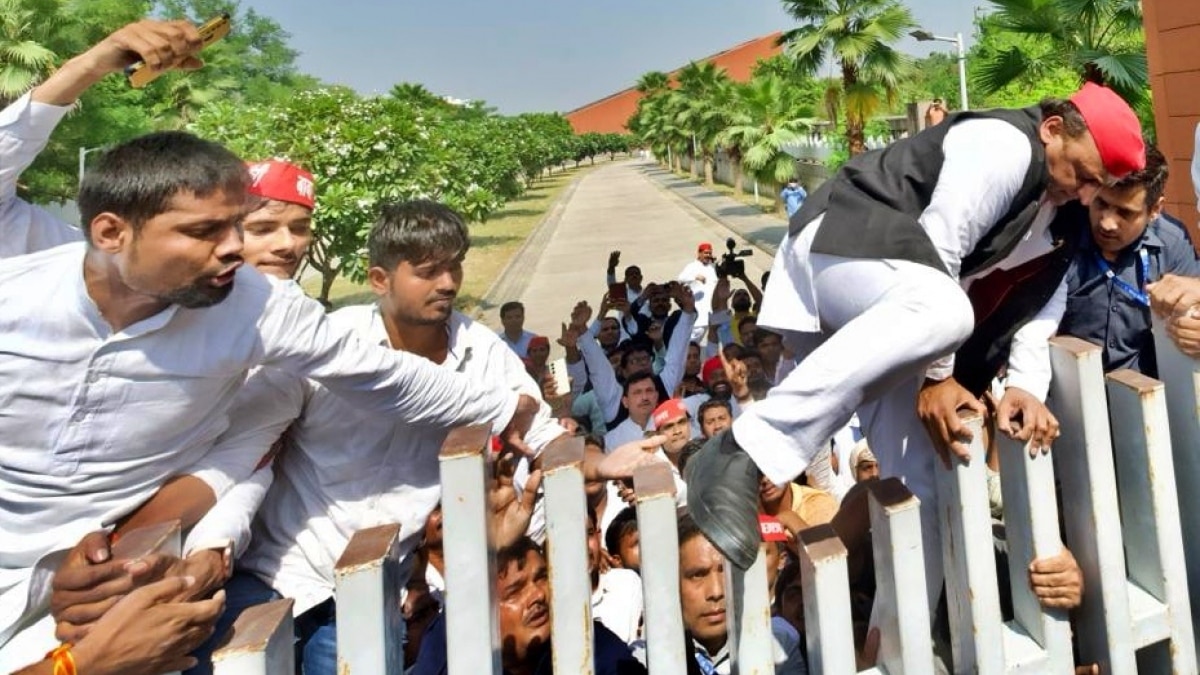 सपा प्रमुख अखिलेश यादव JPNIC का गेट फांदकर अंदर जाते हुए 