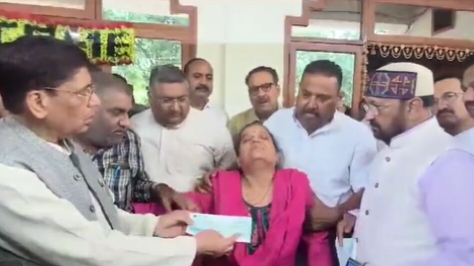 आगरा में मंत्री योगेंद्र उपाध्याय (टोपी लगाए हुए) ने शहीद कैप्टन के परिवार को चेक सौंपा था.