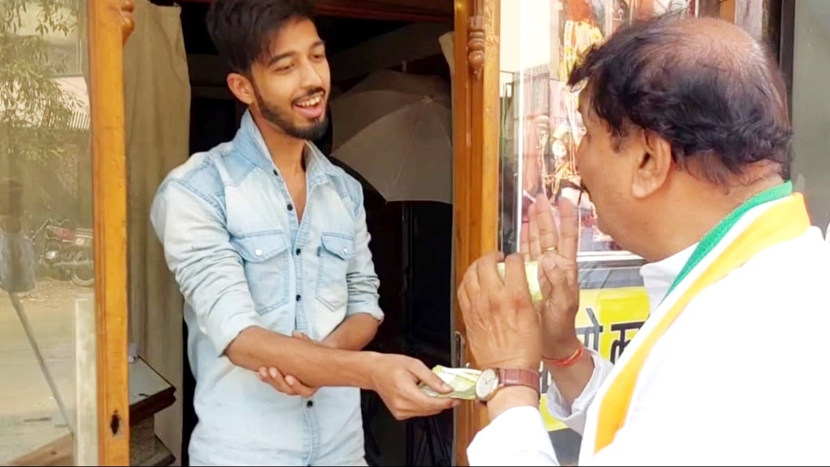 कांग्रेस प्रत्याशी को नोट थमाता हुआ एक युवक.