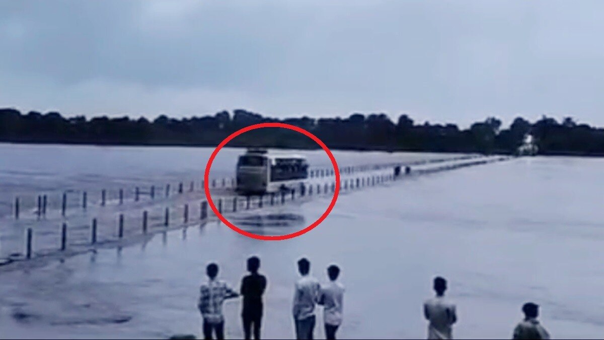 पानी के बहाव के बीच पुल से निकाली यात्री बस.