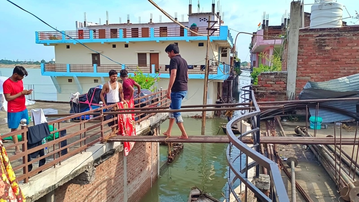 प्रयागराज: बाढ़ के चलते छत फांदकर जाते लोग