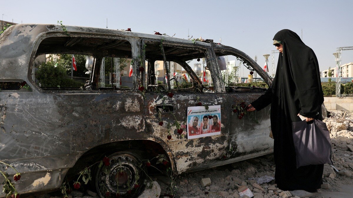 तेहरान में इजरायली हमले में तबाह हुए एंबुलेंस के पास खड़ी महिला (फोटो - रॉयटर्स)